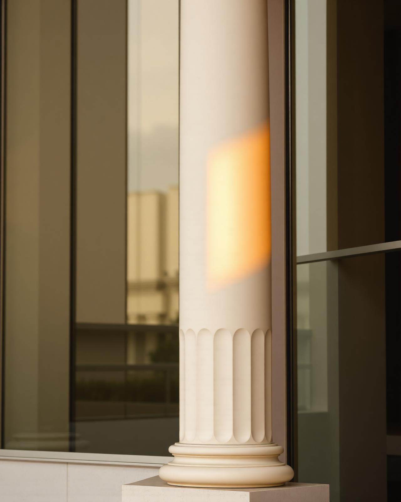 Architectural detail of a classical column meeting a modern glass facade